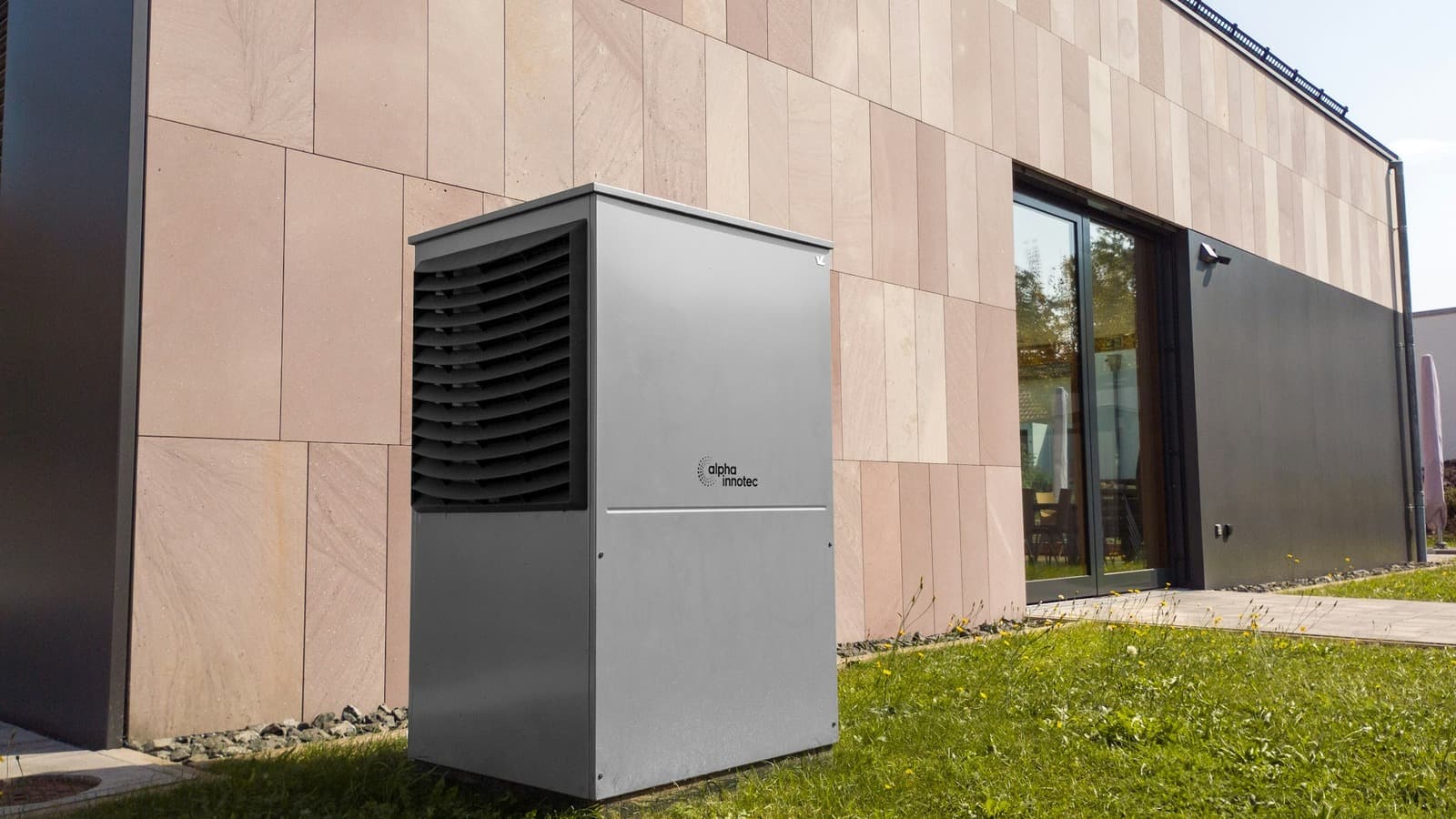 Buitenunit van een warmtepomp naast de gevel van een moderne woning