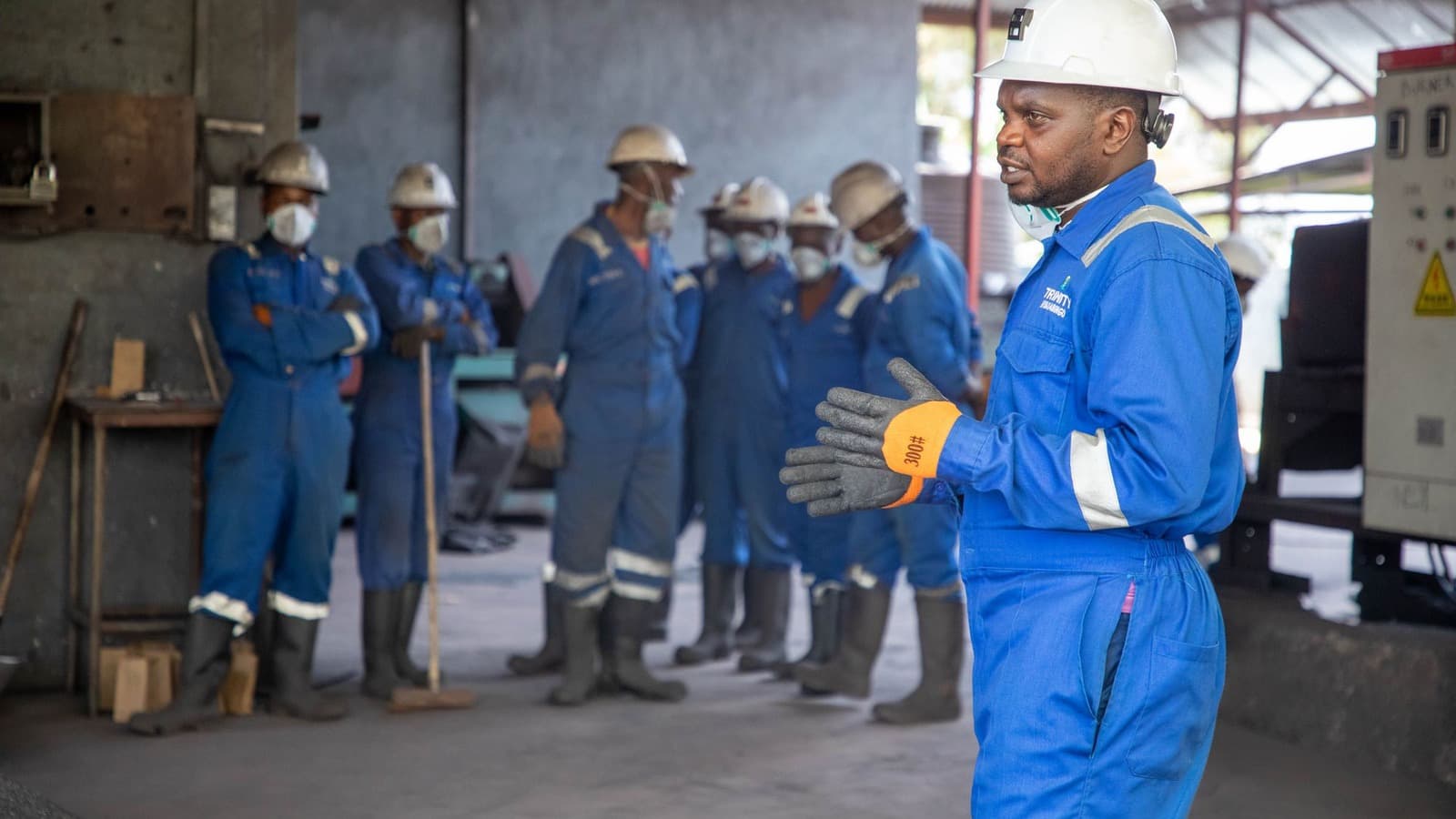 Leidinggevende in beschermende werkkleding geeft een team uitleg in een werkplaats