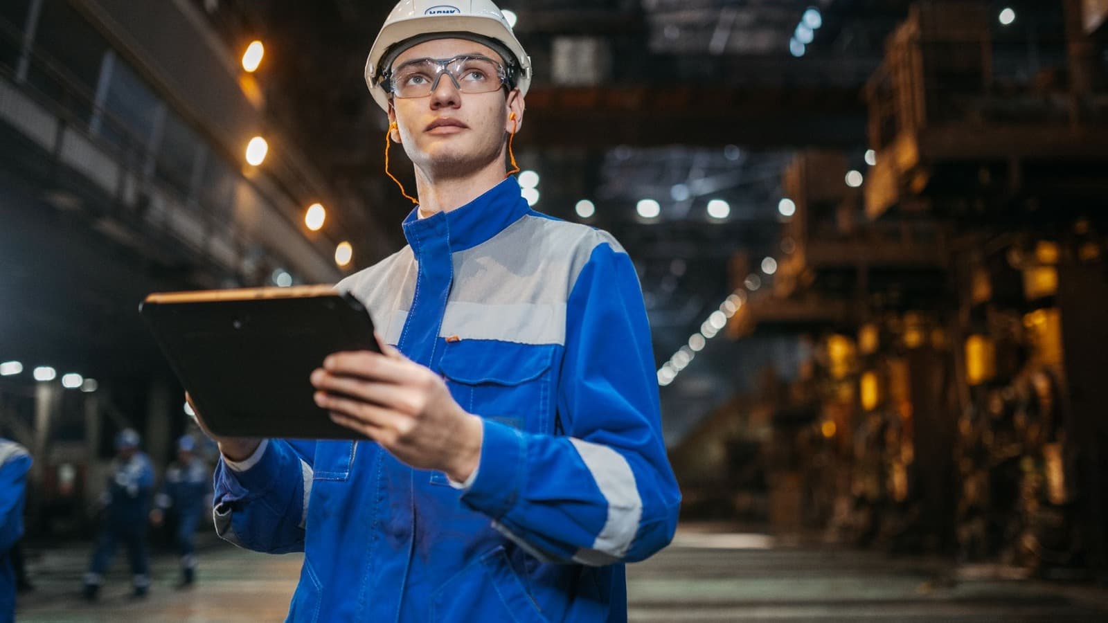 Technische professional met tablet en persoonlijke beschermingsmiddelen in een fabriek
