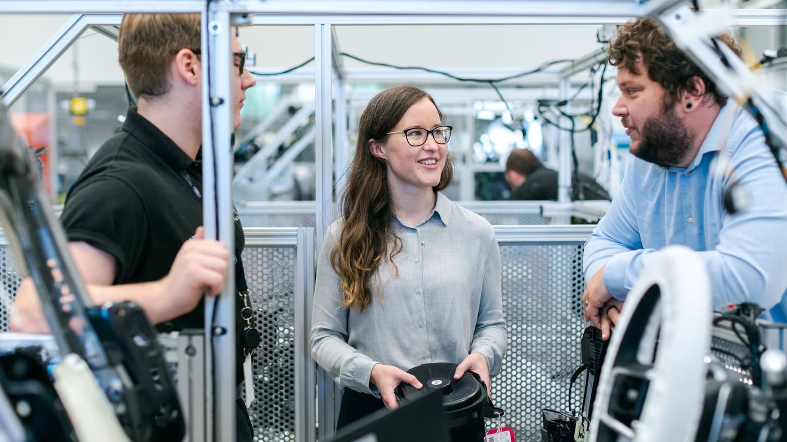Drie technische professionals bespreken werkzaamheden bij een machineopstelling
