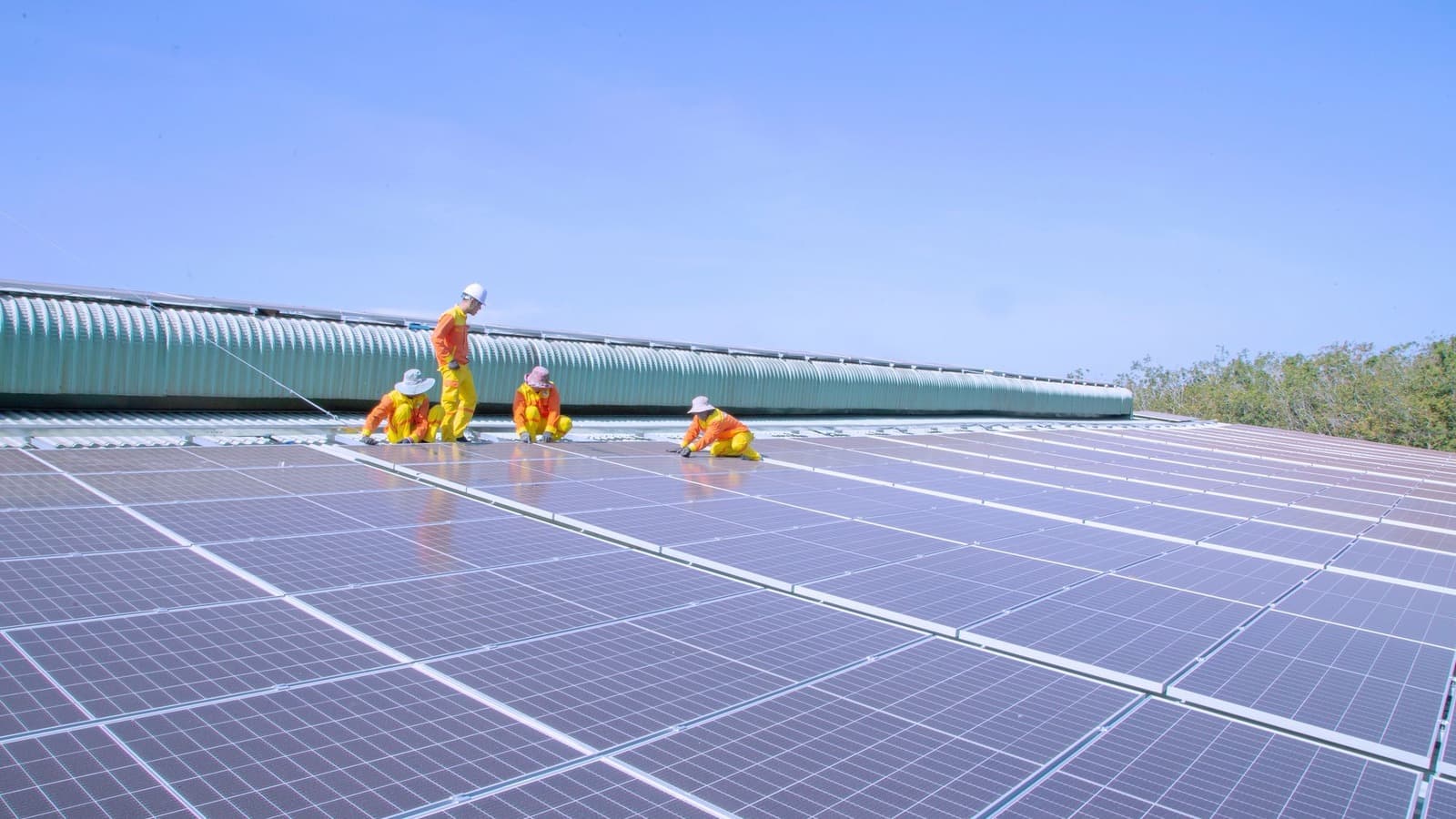 Een team monteurs werkt aan een groot veld zonnepanelen op een bedrijfsdak