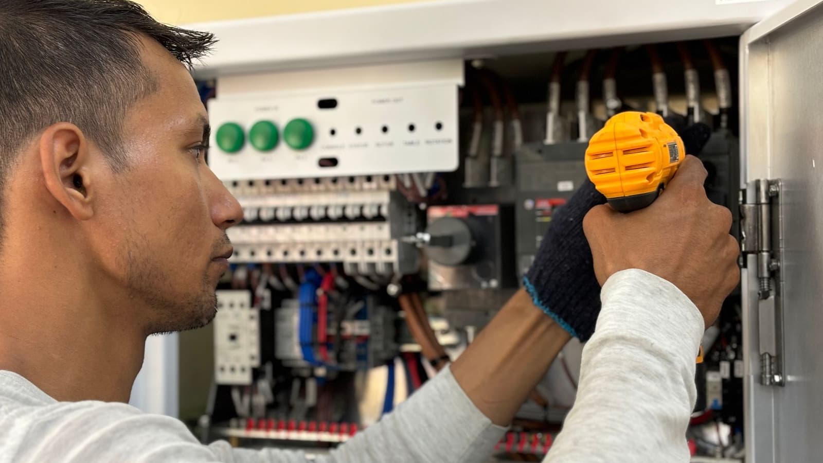 Monteur gebruikt een accuschroefmachine bij een geopende elektrische besturingskast