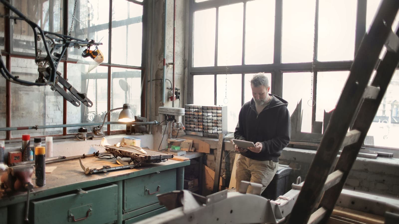 Technische vakman bekijkt informatie op een tablet naast een werkbank vol gereedschap