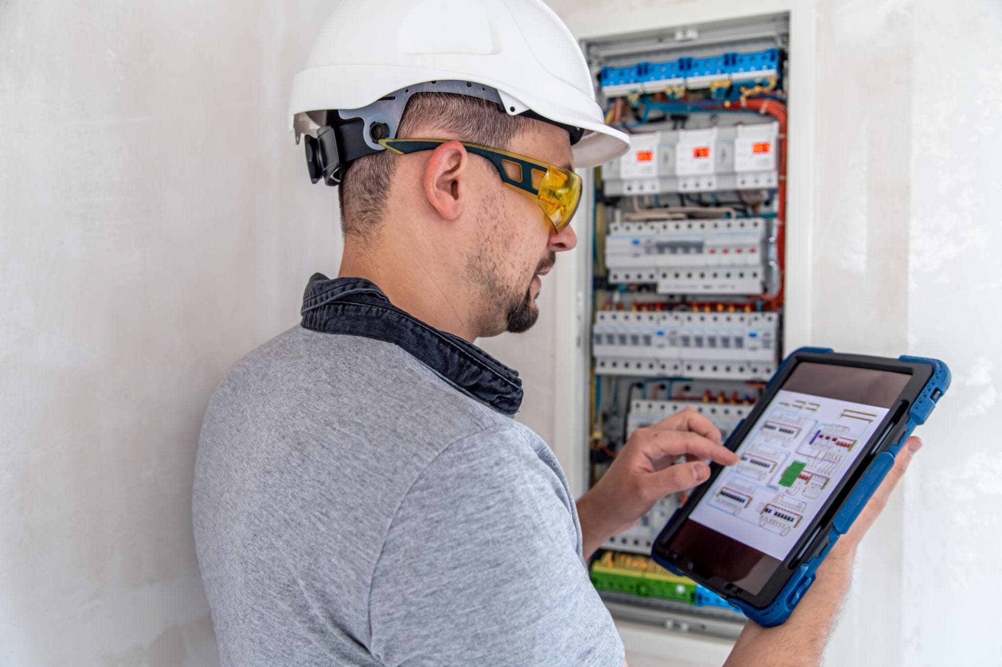 Elektromonteur met een tablet bij een elektrische verdeelkast