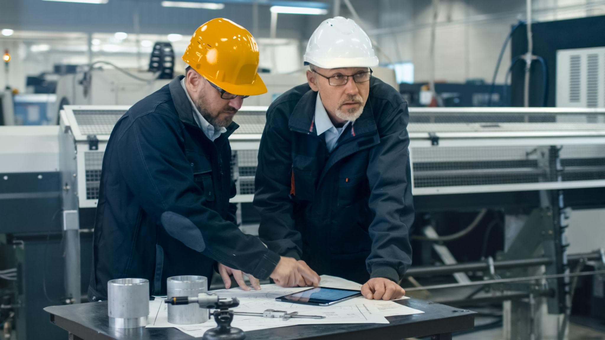 Twee technische professionals bespreken tekeningen in een werkplaats