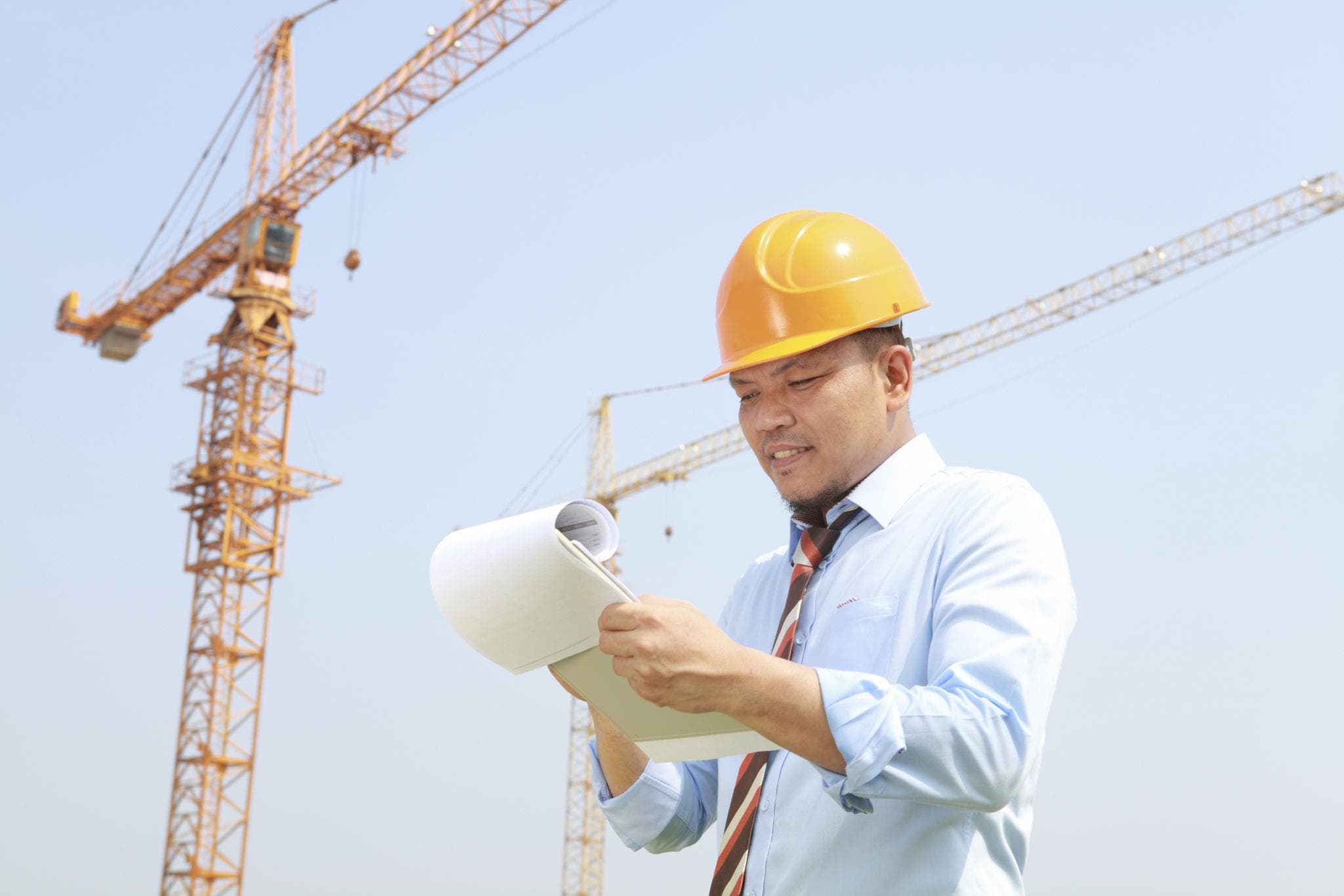Professional met bouwhelm controleert documenten op een bouwplaats