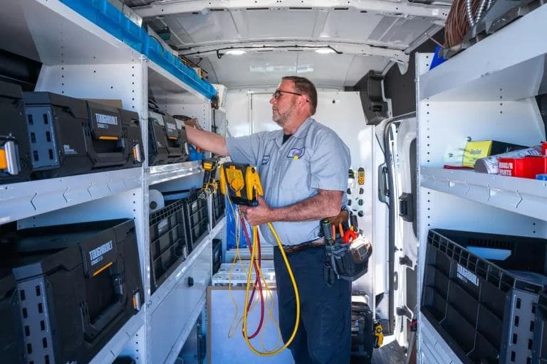 Monteur bij gereedschap en materiaal in een ingerichte bedrijfswagen