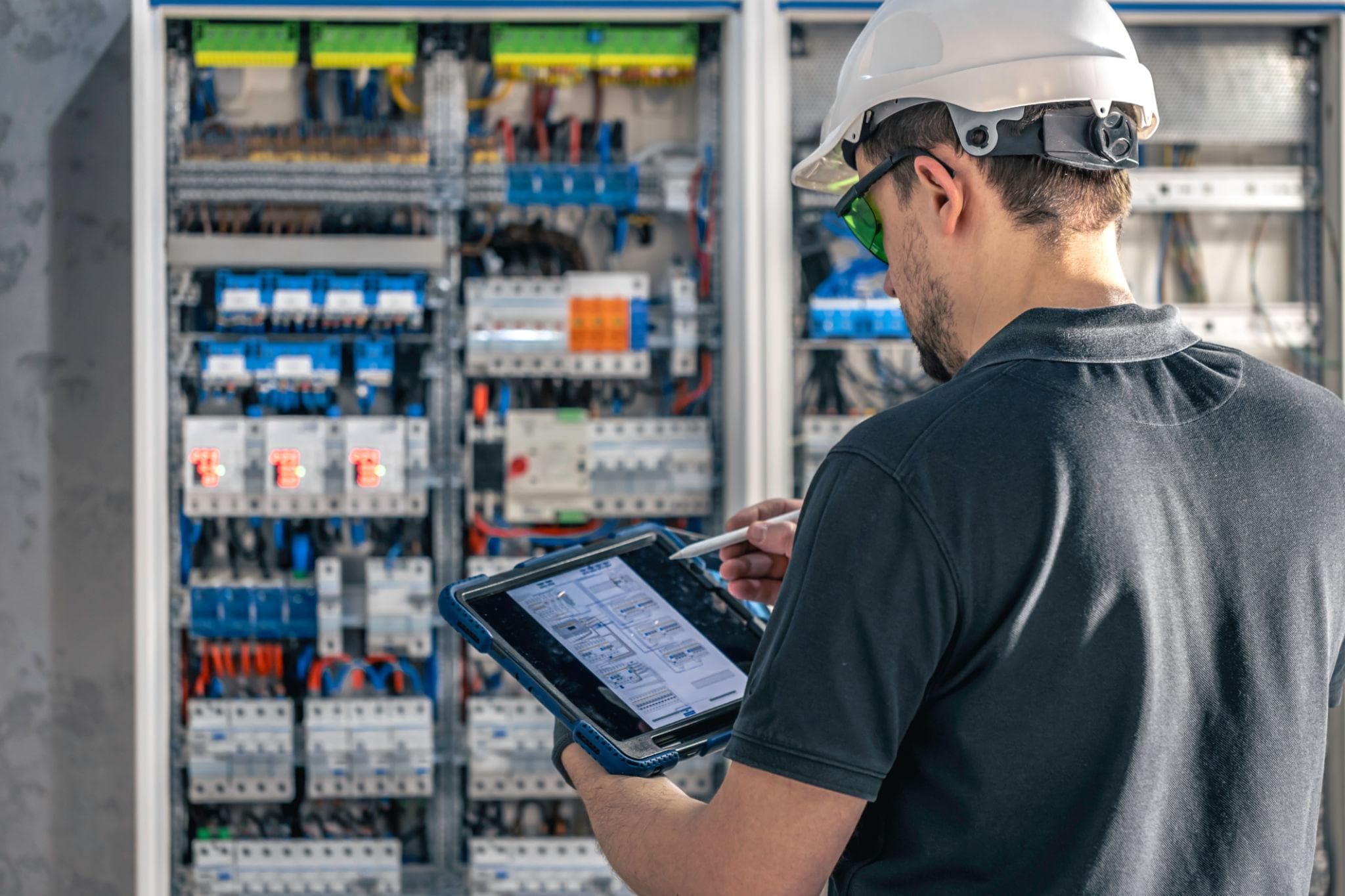 Elektromonteur controleert een verdeelkast met behulp van een tablet